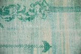 Distressed pile of a vintage Oushak rug, showcasing mint green, aqua blue tones and scrolling vinery.