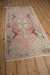 Distressed Oushak runner's stepped geometric medallion, dusty blush field, and pale seafoam border.