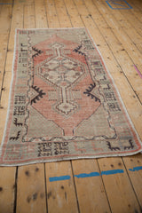 Distressed Oushak runner corner with geometric lattice, soft blush, seafoam, and aubergine hues.