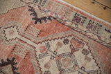 Distressed Oushak rug runner detail showing splayed geometric floral design and textured pile in dusty blush, beige.