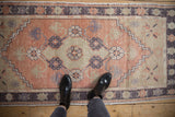 Textured distressed vintage Oushak runner, featuring melon, aubergine, beige floral motifs.