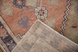 Folded vintage Oushak rug corner revealing distressed terracotta pile and striped woven foundation.