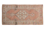 Vintage distressed Oushak runner with dusty rose field and stepped geometric medallion.