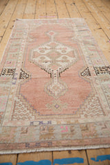 Distressed vintage Oushak runner's stepped medallion, showing geometric floral patterns with pale seafoam and pink.