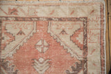 Muted pink and ivory distressed Oushak rug detail with heavy abrashes and visible pile wear.