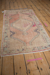 Close-up of distressed Oushak runner end with worn rose and beige geometric motifs and fringe.