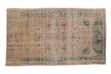 Distressed vintage Oushak rug with floral cameo medallion in antique ivory, dusty blush, forest green.