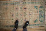 Distressed vintage Oushak rug with worn pile and faded floral patterns.