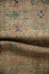 Distressed Oushak rug close-up showing worn pile, visible foundation, and muted floral patterns.