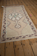 Distressed pile showing geometric stepped medallion and aubergine accents on vintage Oushak runner.