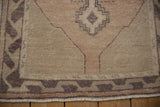 Distressed Oushak runner's lower geometric border in dusty aubergine, with fringe and worn pile.