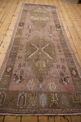 Distressed Oushak runner, showing faded mauve, gold, and brown stepped medallion.