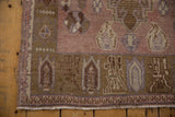 Distressed vintage Oushak rug corner, dusty mauve field, brown geometric border, and fringe.