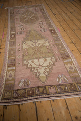 Distressed Oushak runner's textured dusty mauve field and geometric border.