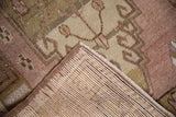 Hand-knotted foundation, intact side cord, and distressed mauve-beige patterns of a vintage Oushak rug.