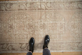 Distressed Oushak runner with muted beige tones and intricate faded floral pattern.