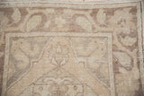 Distressed texture and faded floral motifs in muted beige and brown of a vintage Oushak runner.