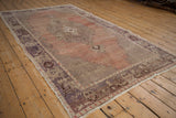 Distressed vintage Oushak rug showing even pile wear, dusty rose field, and muted aubergine border.