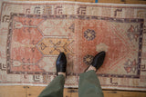 Distressed cantaloupe Oushak rug with germinating floral motifs and worn pile.