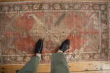 Distressed Oushak rug's diamond medallion, floral pattern, and wear across to knot heads.