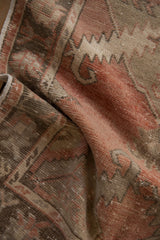 Distressed Oushak rug with visibly worn pile and muted blush, brown, and ivory tones.