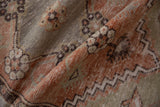 Worn pile of vintage distressed Oushak runner with terracotta floral and zigzag patterns.