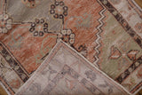 Distressed Oushak runner pile, terracotta and sage, showing wear and hand-knotted foundation.