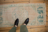Distressed Oushak runner with visible wear and faded beige, seafoam green pattern.