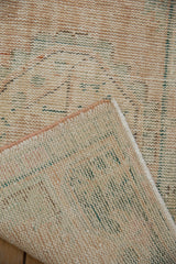 Distressed vintage Oushak rug with worn pile, exposed knot heads, and woven back.