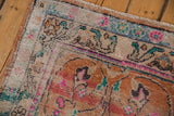 Distressed Oushak rug corner showing worn pile, exposed foundation, and faded floral motifs.
