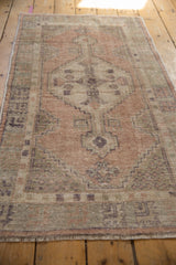 Distressed Oushak rug with stepped geometric pattern in muted apricot and seafoam green.