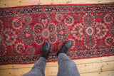 Vintage Persian Dargezine runner's low, even pile on cherry red field with floral motifs.