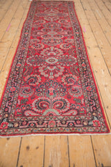 Close-up of Persian Dargezine runner's intricate border and floral vinery in cherry red, blue.