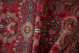 Folded vintage Dargezine rug detail showing cherry red field with scrolling millefleur vinery.