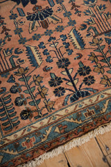 Distressed Lilihan rug's meandering vine main border in dusty rose, navy, copper, with fringe.