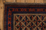 Corner of vintage Belouch rug with geometric starburst and pawn borders.