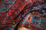 Folded vintage Borchalou rug featuring cherry red field and intricate blue Herati motifs.