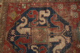 Antique Caucasian rug: worn cloudband medallion in navy and cherry red, pile revealing foundation.