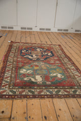 Geometric borders and red field of this antique Caucasian rug, showing wear and tattered ends.