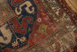 Antique Caucasian rug's worn cherry red and navy blue geometric pile, showing foundation.