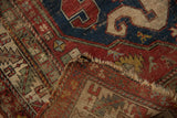 Antique Caucasian rug corner showing its detailed hand-knotted back, tattered fringe, and worn pile.