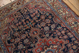 Hand knotted Persian rug detail: navy field, faded blush, sky blue floral pattern.