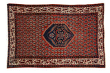 Vintage Serbend rug with a navy shield medallion on a brick red field of repeating staggered motifs.