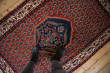 Scale view of a vintage Serbend rug's navy medallion and patterned brick-red field.