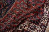 A draped corner of the vintage Serbend rug showing the intricate ivory border and red field.