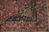 Vintage Meshed rug corner with cochineal red field, intricate blue lotus vinery, and fringe.