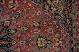 Intricate vinery and blossoms detail on the vintage hand knotted Meshed rug's cochineal red field.