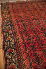 Distressed vintage Borchalou carpet border with beige, navy, and red stylized floral cartouches showing even wear.