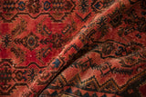 Distressed Borchalou rug showing worn raspberry red pile, navy and brown repeating floral patterns.