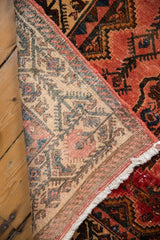 Vintage Borchalou rug's hand-knotted foundation, fringed edge, and distressed raspberry pile.